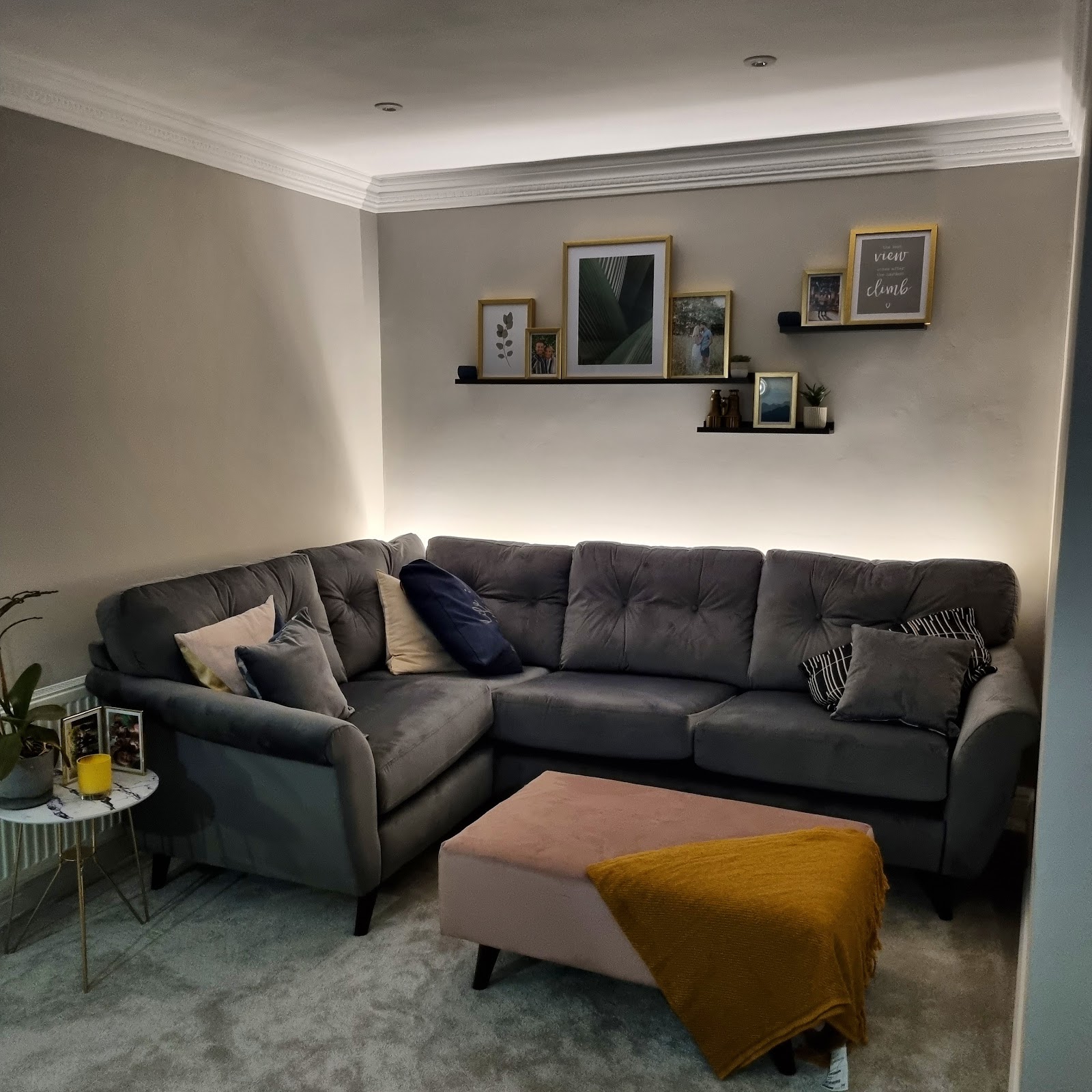Concealed LED cove lighting washing a lounge ceiling and coving — a warm layer above the downlights.